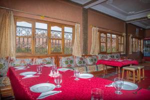 a dining room with red tables and chairs and windows at Hotel Awayou in Bou Drarar