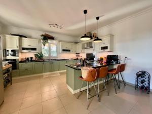 a kitchen with green cabinets and a island with bar stools at Casa do Monte in Loulé