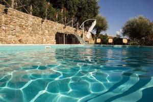 Sessa CilentoにあるPalazzo del Baglivo Cilento Hotel & Spaの石壁の青い水のスイミングプール