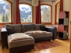 a living room with a couch and two windows at BnB Försterlodge in Schwarzsee