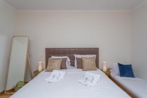 Una cama con sábanas blancas y almohadas. en BeGuest Vasco da Gama Apartment, en Lisboa