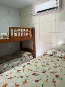 1 Schlafzimmer mit 2 Etagenbetten mit Blumenbettdecke in der Unterkunft Apartamento familiar aconchegante in Maragogi