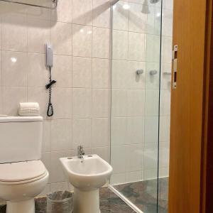 uma casa de banho com um WC e um chuveiro com um telefone em Hotel & Residência Alphaville em Barueri