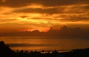 um pôr do sol sobre a água com pessoas na praia em Vista del Pacifico. em Quepos