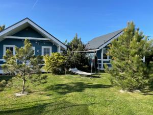 a house with a yard with trees and a swing at By The Sea Lodges in Wrzosowo