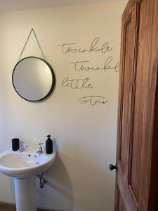 a bathroom with a sink and a mirror on the wall at Boujie Barn- Shippon in Waterfall