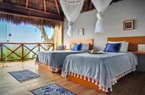 two beds in a room with a view of the ocean at Xinalani Retreat Mexico in Qumiste