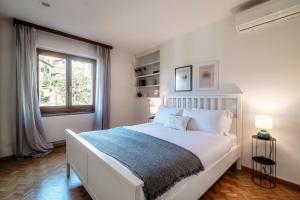 - une chambre blanche avec un grand lit et une fenêtre dans l'établissement Lilia Apartment by Quokka 360 - large flat with panoramic view of Locarno, à Gordola
