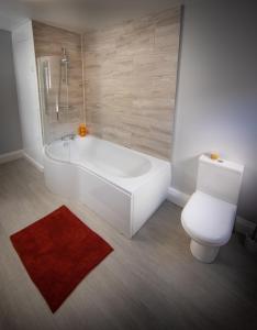 a bathroom with a white tub and a toilet at Loft Apartment, Keswick in Keswick
