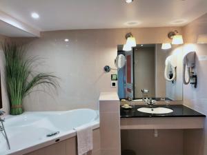 a bathroom with a tub and a sink at Logis HOTEL RESTAURANT La Régence in Cherbourg en Cotentin