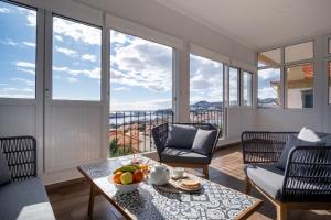 een woonkamer met een tafel, stoelen en ramen bij Pi Houses in Funchal