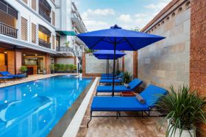 Blanc Smith Hotel في سيام ريب: مسبح وكراسي الصالة الزرقاء ومظلة