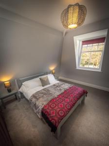 a bedroom with a bed with a red blanket and a window at Loft Apartment, Keswick in Keswick