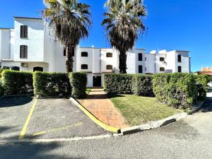 un edificio blanco con palmeras en un aparcamiento en Vilamoura Brightness With Pool by Homing, en Vilamoura