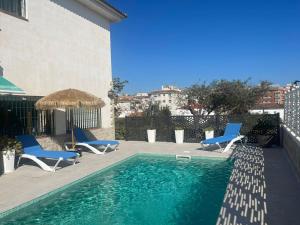 una piscina con sillas azules y un edificio en Casa unifamiliar en Calafell, en Calafell