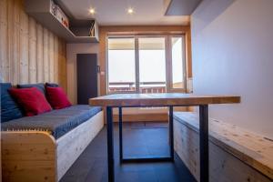 LʼHuezにあるComfortable studio with balcony - Huez - Welkeysのテーブル、ベンチ、窓が備わる客室です。