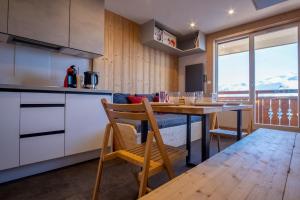 a kitchen with a table and a dining room at Comfortable studio with balcony - Huez - Welkeys in LʼHuez