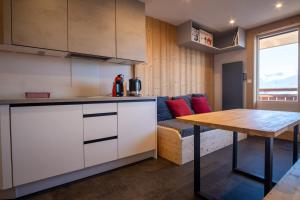 uma cozinha e sala de estar com uma mesa e um sofá em Comfortable studio with balcony - Huez - Welkeys em LʼHuez