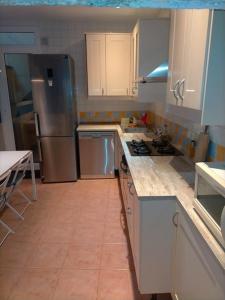 una cucina con armadietti bianchi ed elettrodomestici in acciaio inossidabile di Preciosa casa de 2 pisos a 50 metros de la playa a Canet de Mar