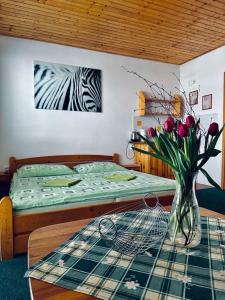Un dormitorio con una cama y una mesa con un jarrón de flores en Penzion pod Brehom en Terchová