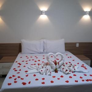 Una cama con dos cisnes blancos formando un corazón en Rosa Vilma Hotel, en Chapadão do Sul