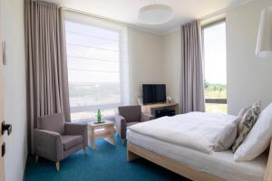 ein Hotelzimmer mit einem Bett, zwei Stühlen und einem Fenster in der Unterkunft Hotel Vinice Hnanice in Hnanice