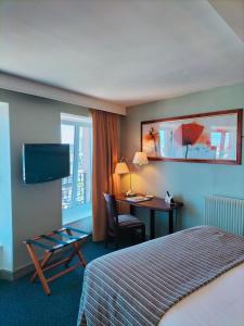 シェルブール・アン・コタンタンにあるLogis HOTEL RESTAURANT La Régenceのベッドとデスクが備わるホテルルームです。
