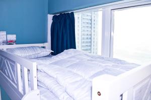 Cama blanca en habitación con ventana en Hawana Hostel, en Dubái