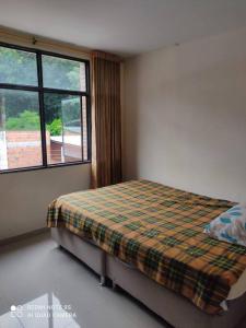 1 dormitorio con 1 cama con manta a cuadros y ventana en HERMOSO APARTAMENTO CON TERRAZA, en Ibagué