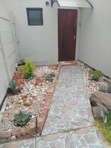einen Garten mit Felsen und einen Gehweg mit Tür in der Unterkunft Diamonds on 2 Patricia Place in King Williamʼs Town