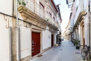 an alley with buildings and a red door at Viana Central - Historical City Centre Apartment in Viana do Castelo