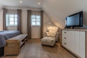 a bedroom with a bed and a tv and a chair at Reetdachhaus Dünenkoog Reetdachhaus Dünenkoog in Tating