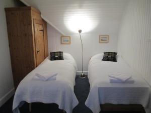 two beds in a small room with white sheets at The Loan in Achiltibuie