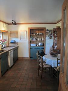 a kitchen with a table and chairs and a kitchen with blue cabinets at The Loan in Achiltibuie