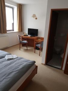 Hotel zur Altstadt في Calbe: غرفة نوم بسرير ومكتب مع تلفزيون