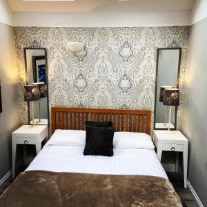 a bedroom with a bed with two night stands and two mirrors at Sheildaig Farm in Balloch