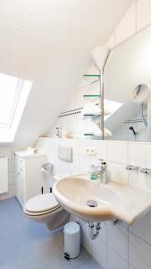a white bathroom with a sink and a toilet at Ferienwohnung Forggensee in Roßhaupten