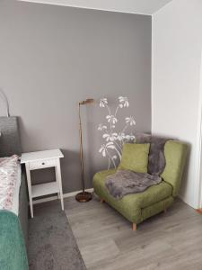 ein Wohnzimmer mit einem grünen Stuhl und einem Tisch in der Unterkunft 57 Kauppakatu in Varkaus