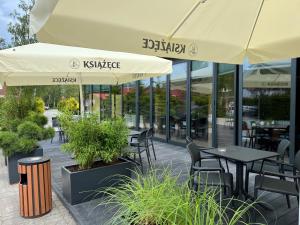 un patio al aire libre con mesas, sillas y sombrillas en BURSZTYN - BERNSTEIN APARTMENTS, en Dąbki