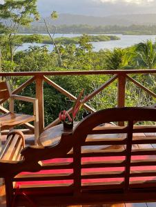 a wooden bench on a balcony with a view of a river at Eden Jungle Lodge in Bocas del Toro