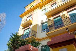 un edificio amarillo con balcones y una palmera en Ostia Holiday Colibrì, en Lido di Ostia