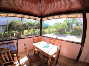 einen Tisch und Stühle in einem Zimmer mit Fenstern in der Unterkunft Pousada Casa Rosa in Alto Paraíso de Goiás