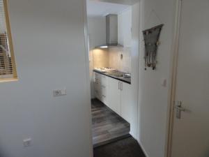 Appartement Schuitvlot في دومبورغ: مطبخ صغير مع دواليب بيضاء وممر
