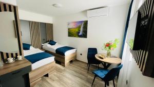 a small room with two beds and a table at M apartmani in Lukavica