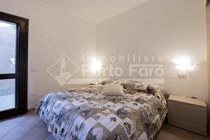帕勞的住宿－L325 - Bilocale con giardino e vista mare panoramica a Porto Mannu，卧室配有一张床,墙上有标志