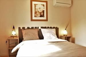 a bedroom with a white bed with two lamps at Small House with pool in Bénesse-Maremne