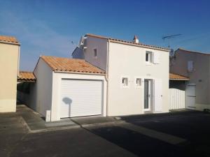 un groupe de bâtiments avec des portes de garage blanches dans l'établissement Maison à 300 m de la plage., à La Cotinière