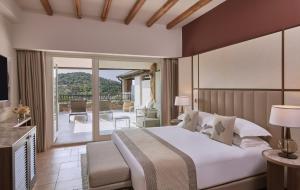 a bedroom with a large bed and a balcony at Conrad Chia Laguna Sardinia in Chia