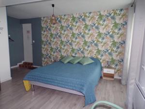 um quarto com uma cama azul e um papel de parede tropical em A la Belle Etoile em Méry-sur-Cher
