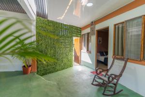 Habitación con silla y pared verde en El Cocobolo Food&Rest Room 3 Bed and Breakfast WiFi AC Pkg gratis, en Liberia